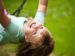Kinder Mädchen schaukelt und lächelt dabei